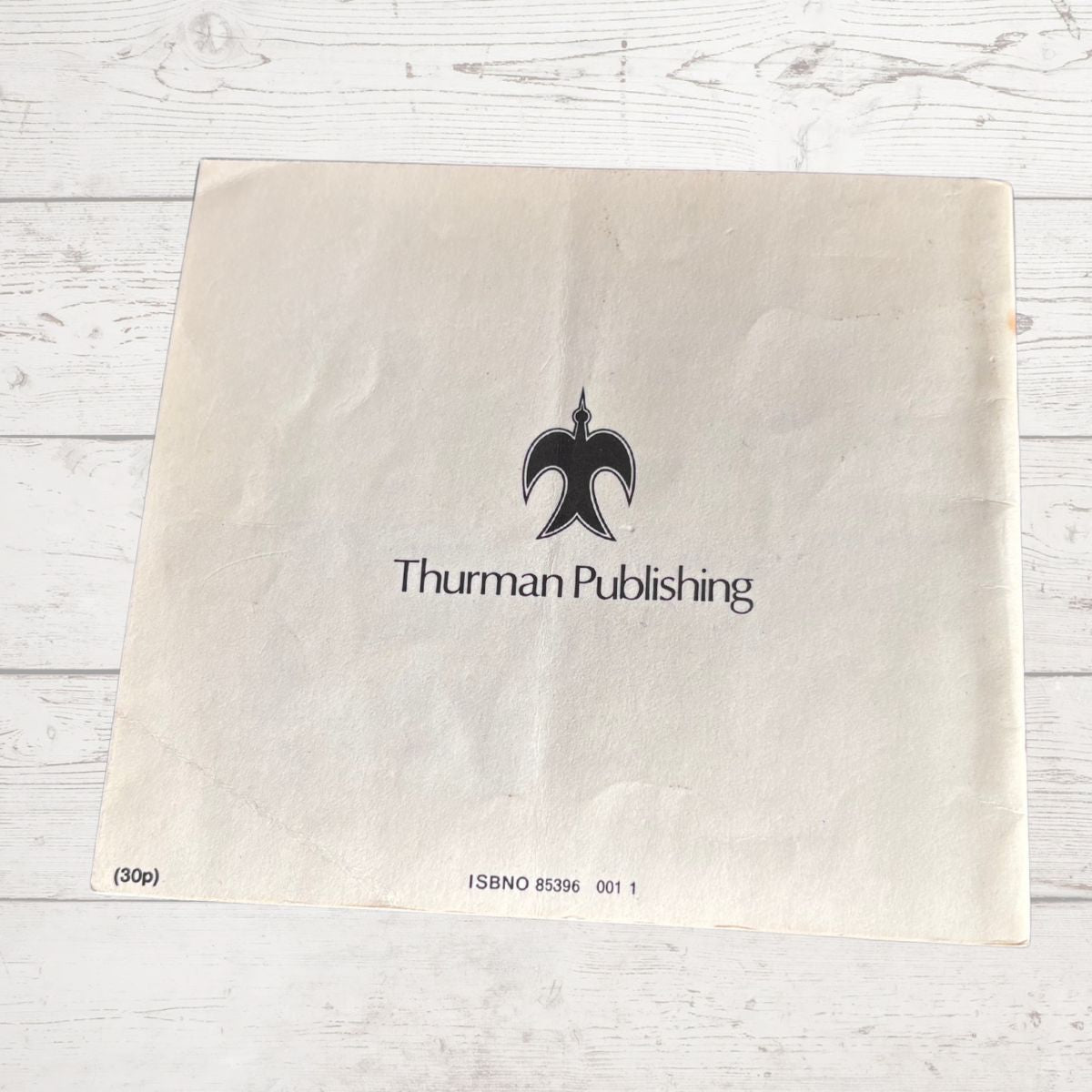 Beige paper with 'Thurman Publishing' logo on a light wooden surface