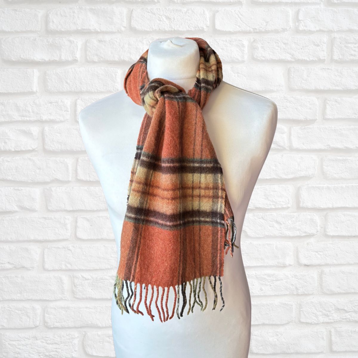 Plaid scarf on a mannequin against a white brick wall