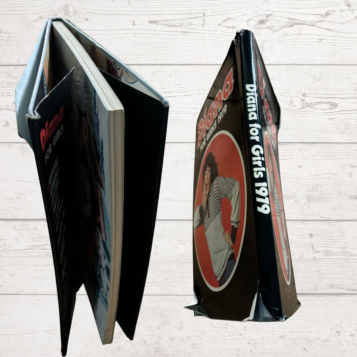 Open book showing the spine and corners with text and graphics on a wooden surface