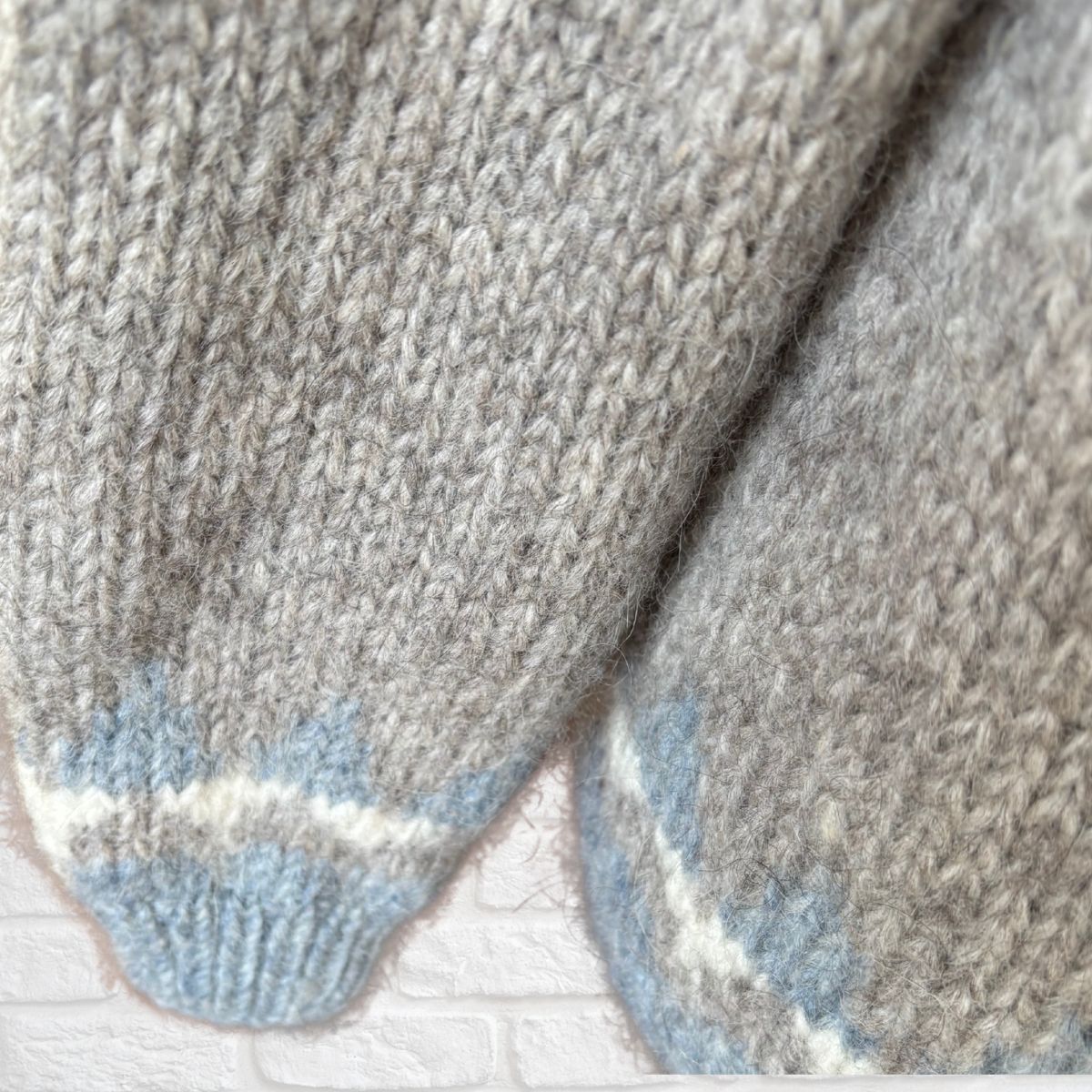 Close-up of grey knitted jumper sleeves blue accents on a light background