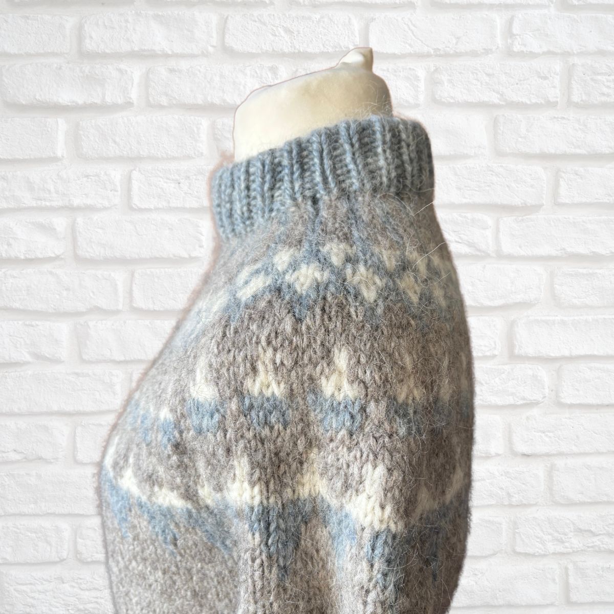 Knitted sweater on a mannequin against a white brick wall background