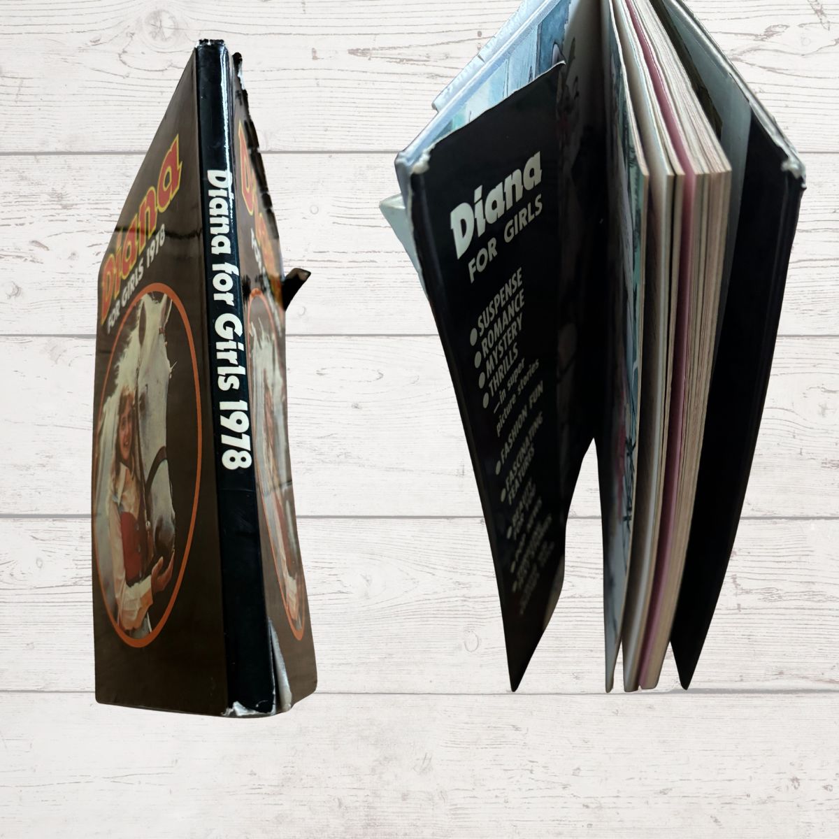 Open book spine and corners with visible text and images on a wooden surface