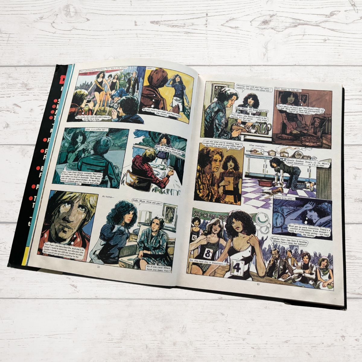 Open comic book with multiple panels on a wooden surface