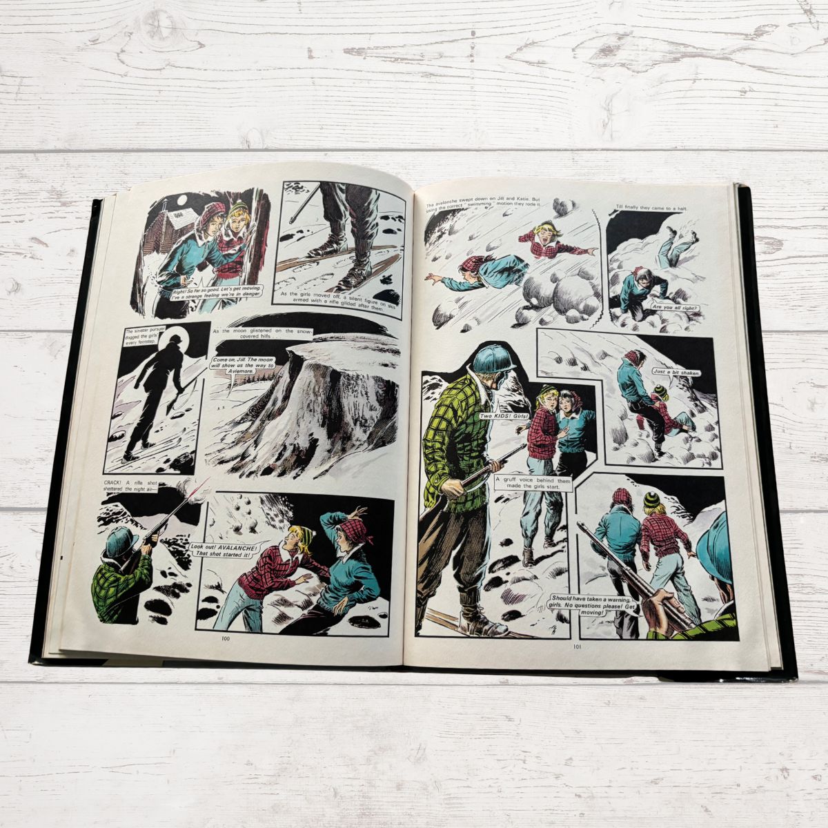 Open book displaying comic book pages with illustrations of people in a snowy landscape.