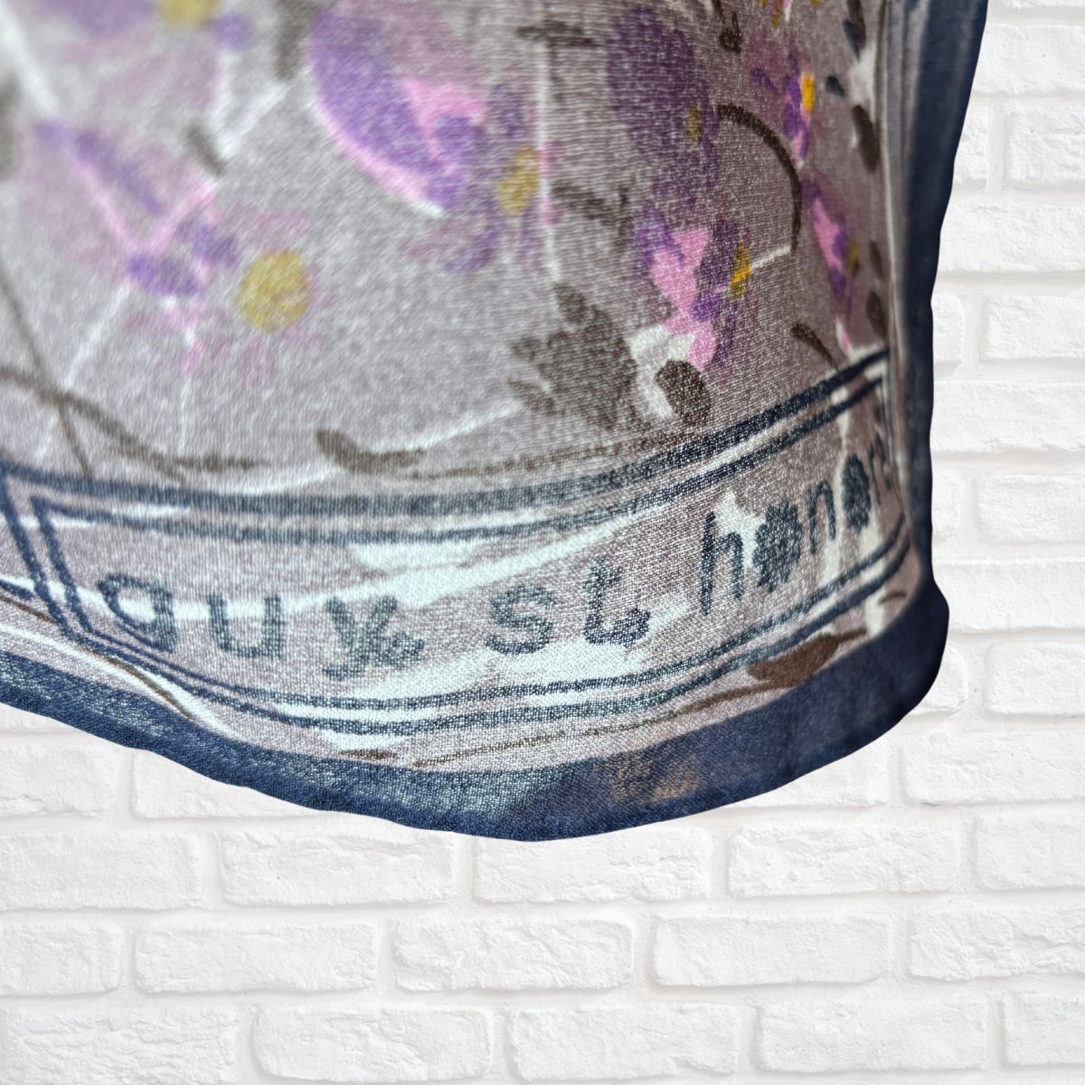 Close-up of a fabric with floral patterns and text on a white brick background