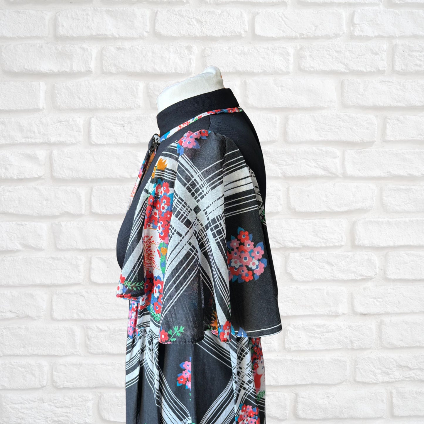 70s vintage maxi dress by Richard Shops with black high neck bodice and floral skirt - topside view of caped floaty sleeves
