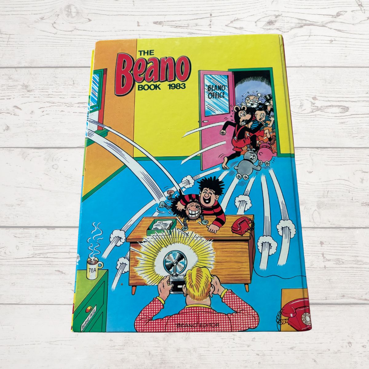 Vintage 'The Beano Book' 1983 comic book cover on a wooden surface