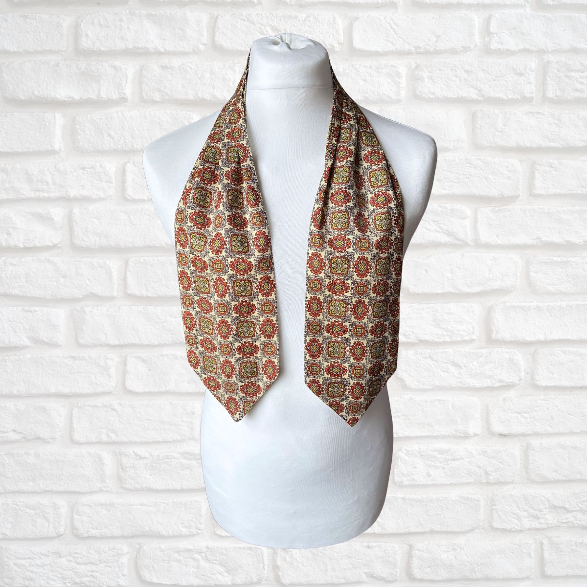 Patterned cravat on a mannequin against a white brick wall background