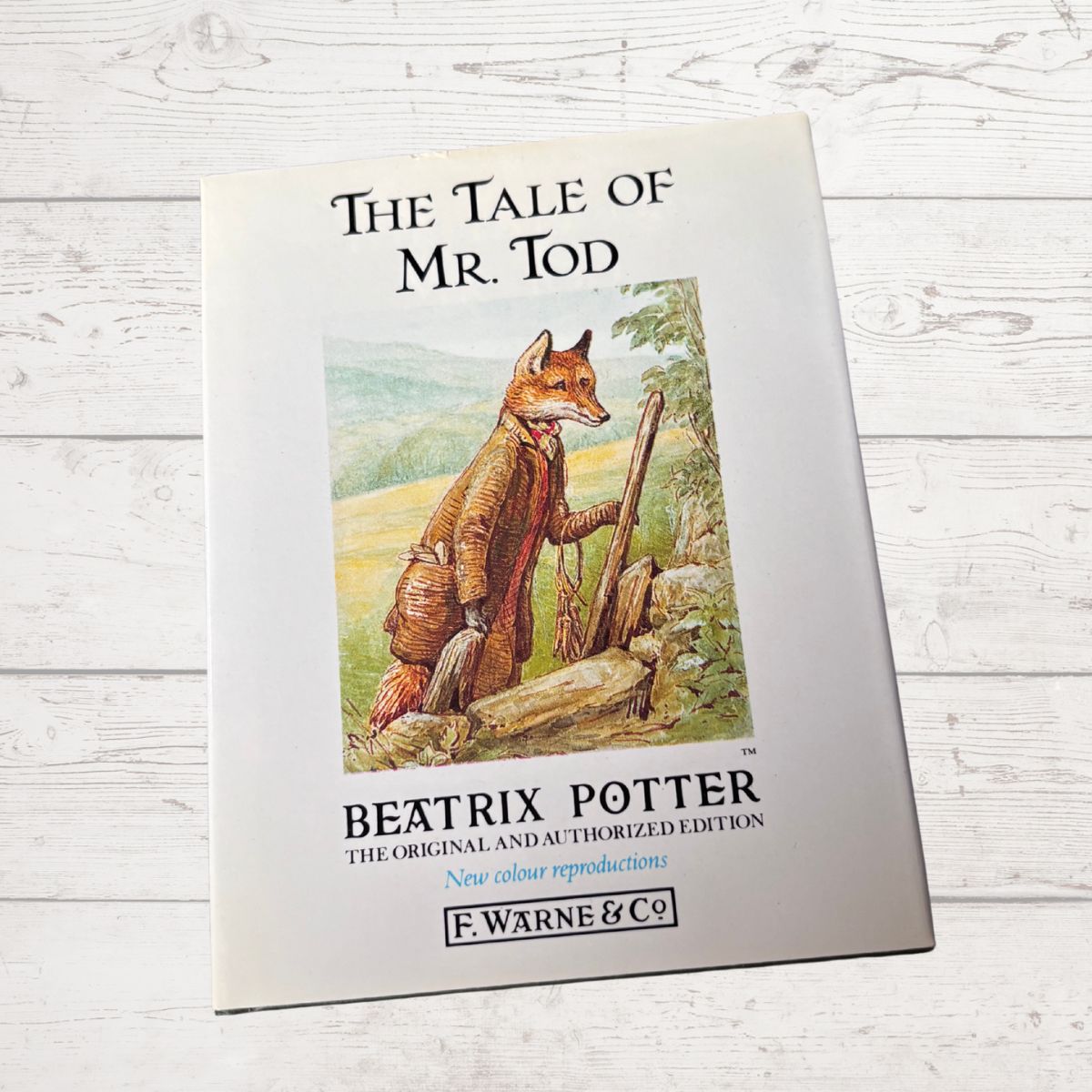 Book cover of 'The Tale of Mr. Tod' by Beatrix Potter on a wooden surface