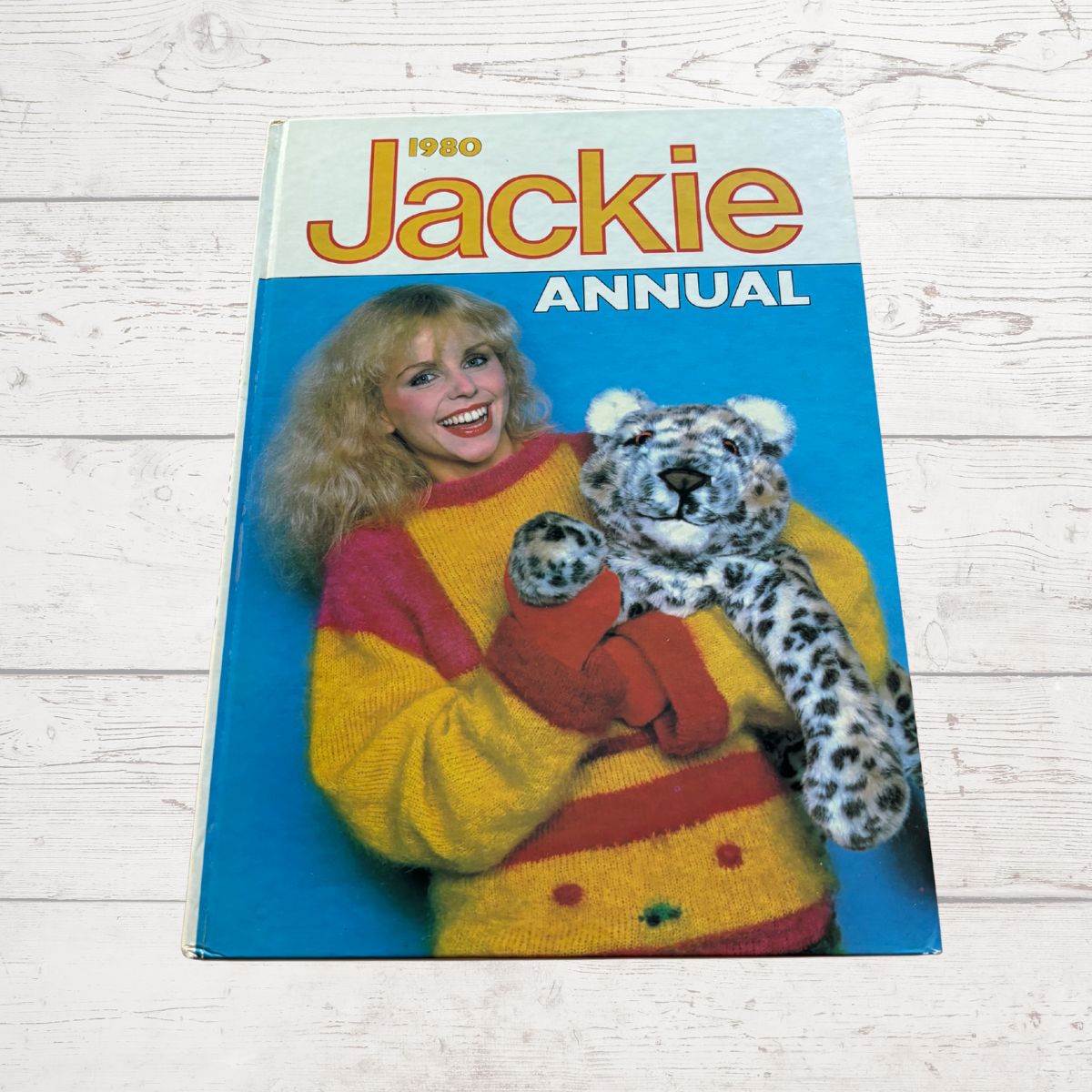 1980 Jackie Annual cover with a woman holding a stuffed animal on a wooden surface