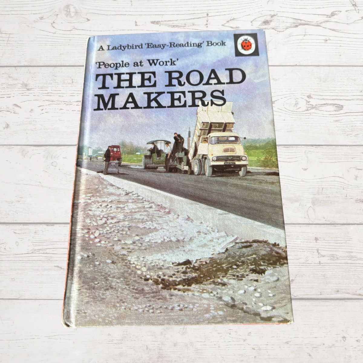 Book titled 'The Road Makers' on a wooden surface