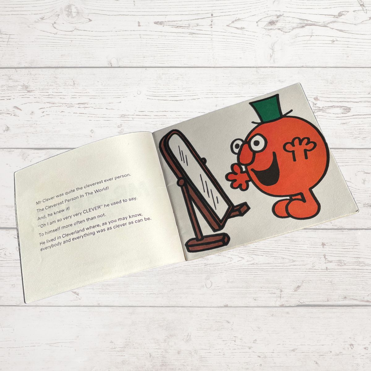 Open book with a cartoon character on a wooden surface