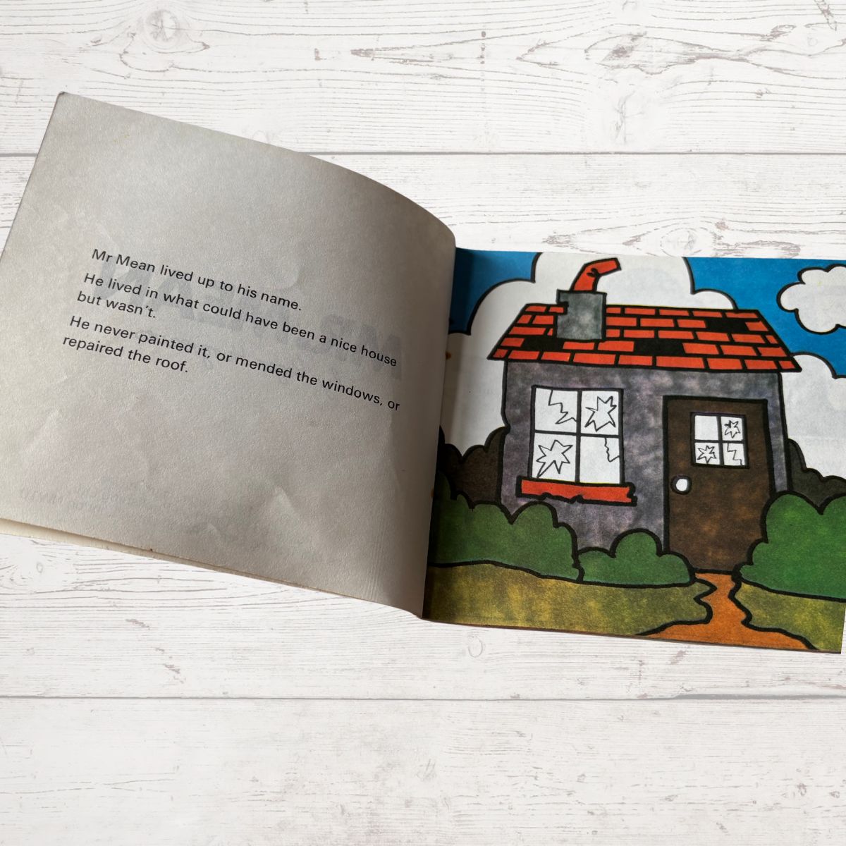 Open book with a colorful illustration of a house on a white wooden surface