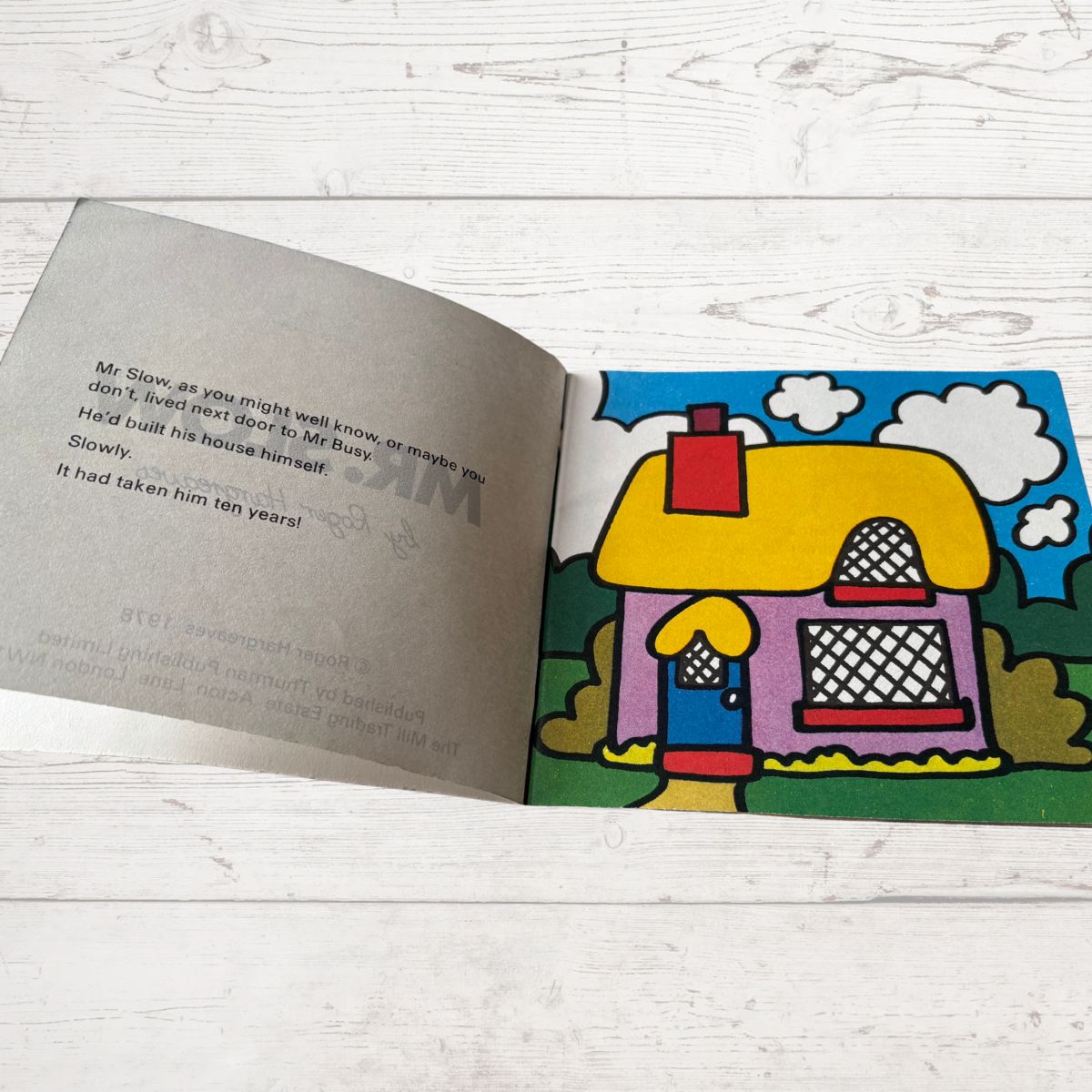 Open book with a colorful illustration of a house on a wooden surface