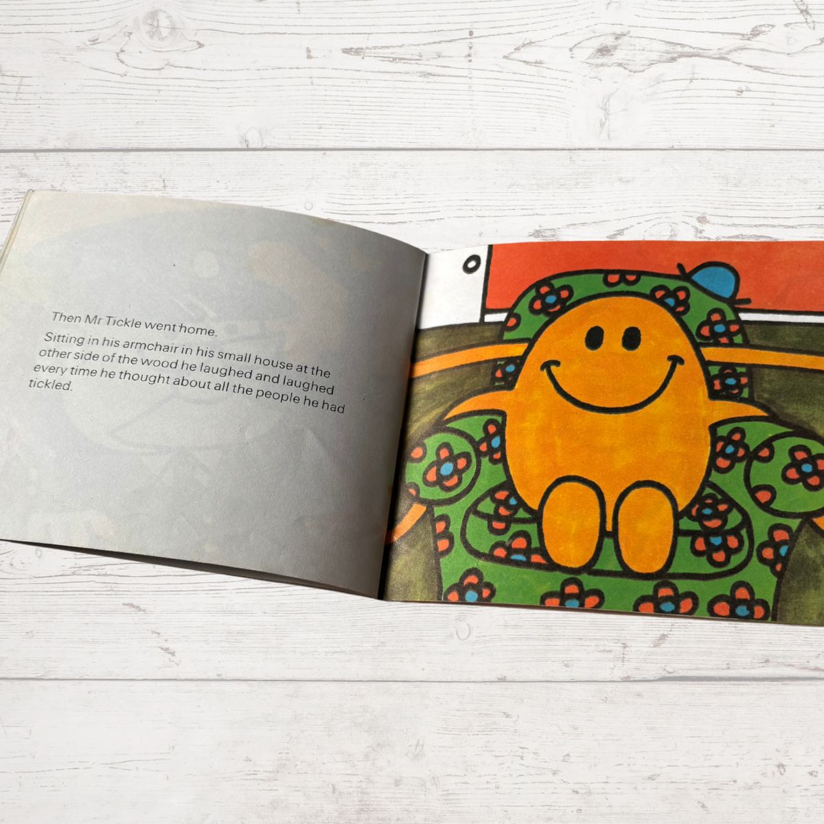 Open book with a colorful illustration of a smiling character on a wooden surface