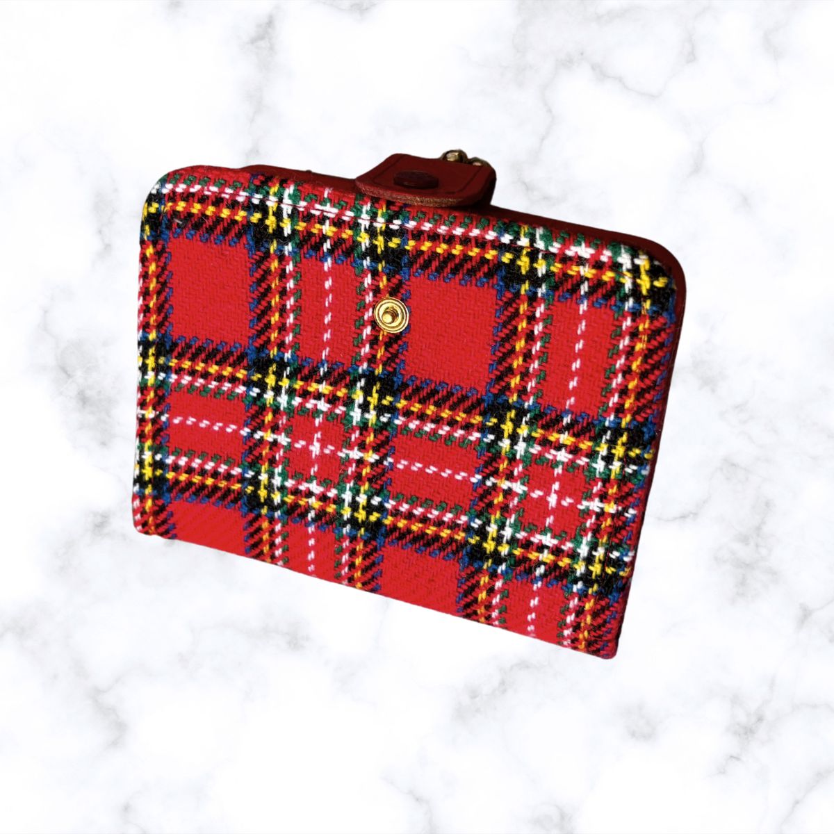 Plaid wallet with red, blue, and yellow pattern on a white marble background
