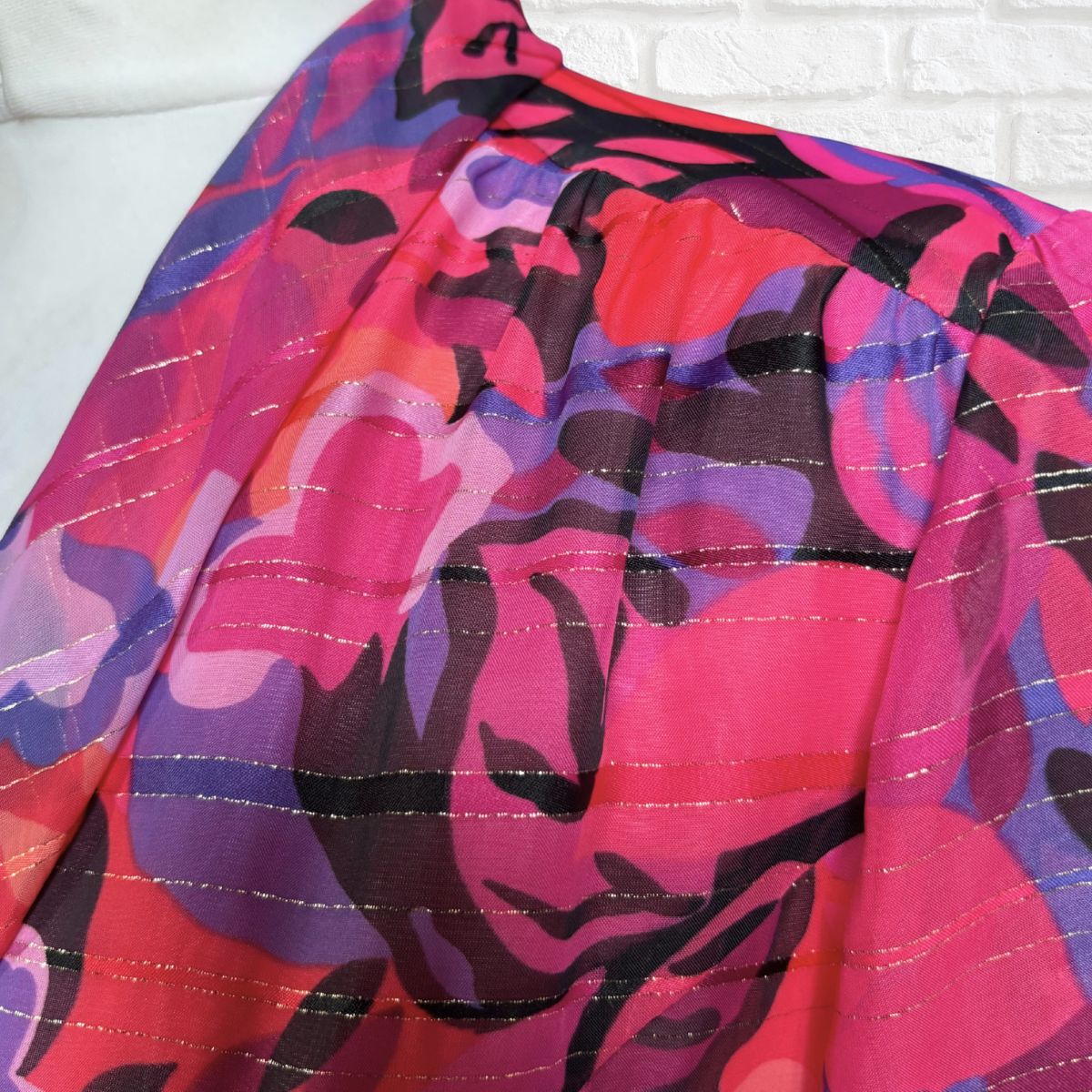 Colorful patterned fabric with pink, purple, and black design on a white background