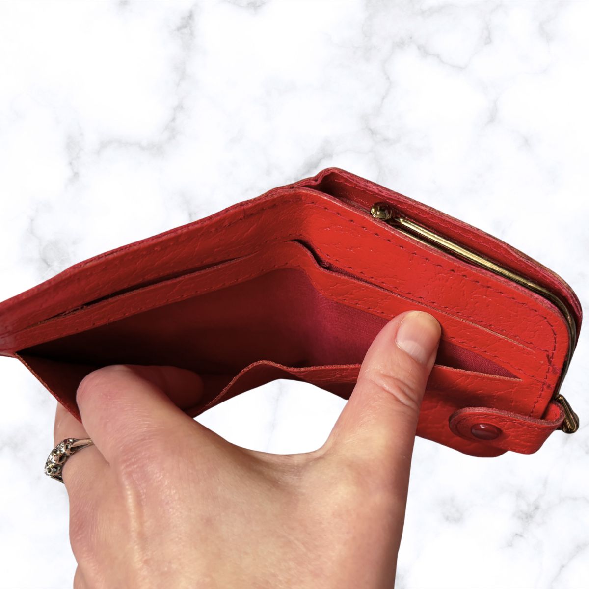 Red wallet held by a hand against a white background