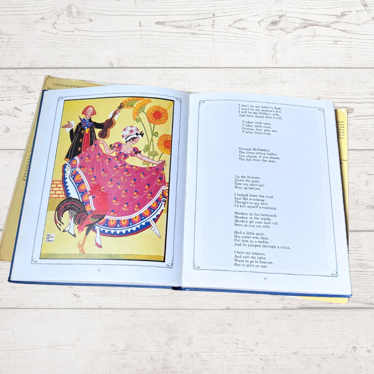 An open children's book lying flat on a light wood surface, showing a colorful illustration of a dancing couple on the left page and printed text on the right page.