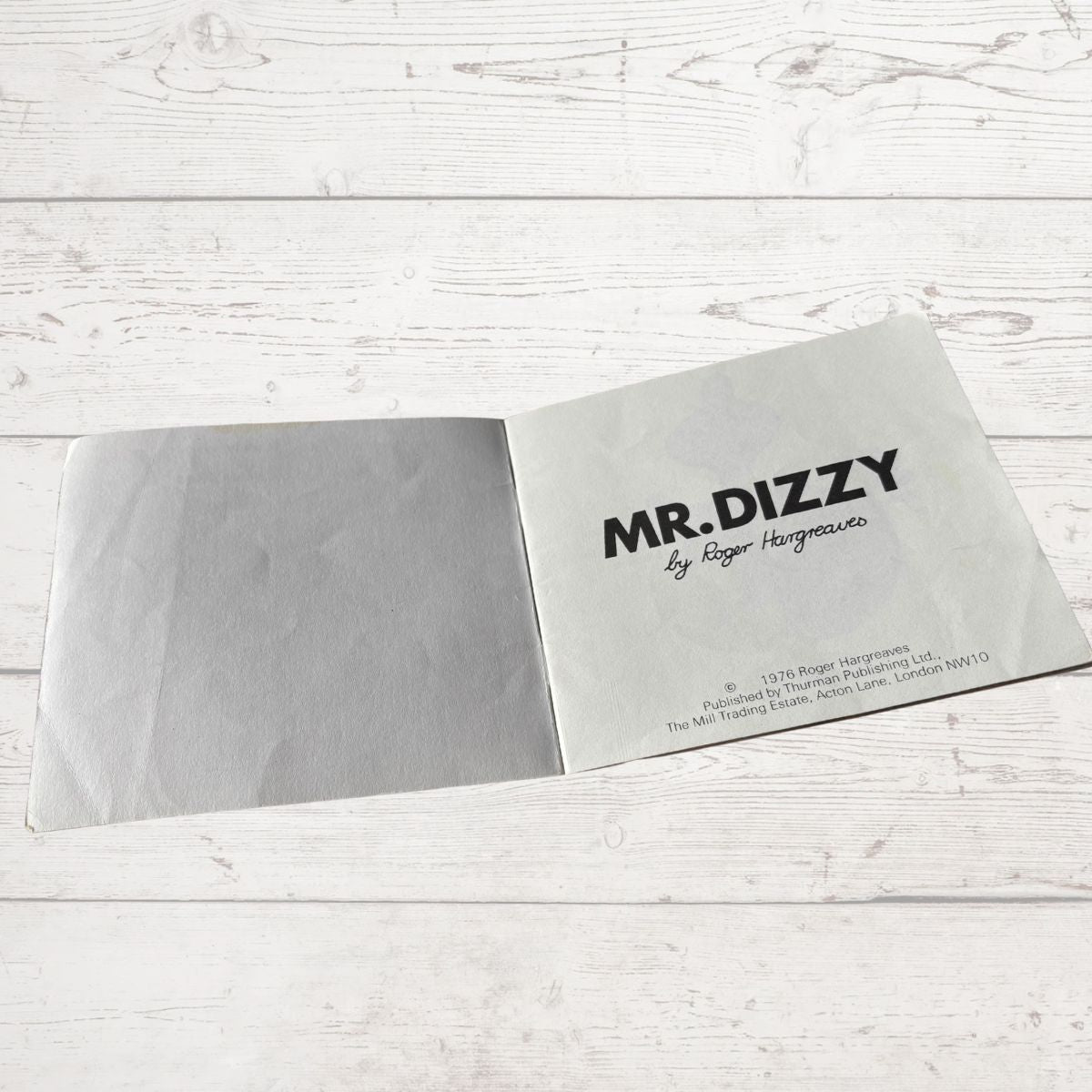 Book with 'MR. DIZZY' branding on a light wooden surface