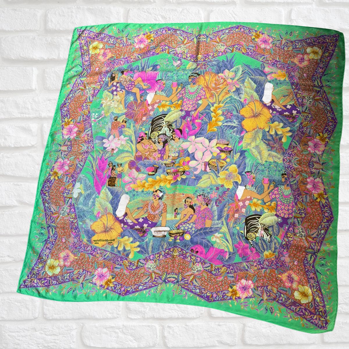 Colorful scarf with a floral and nature-themed design on a white brick background