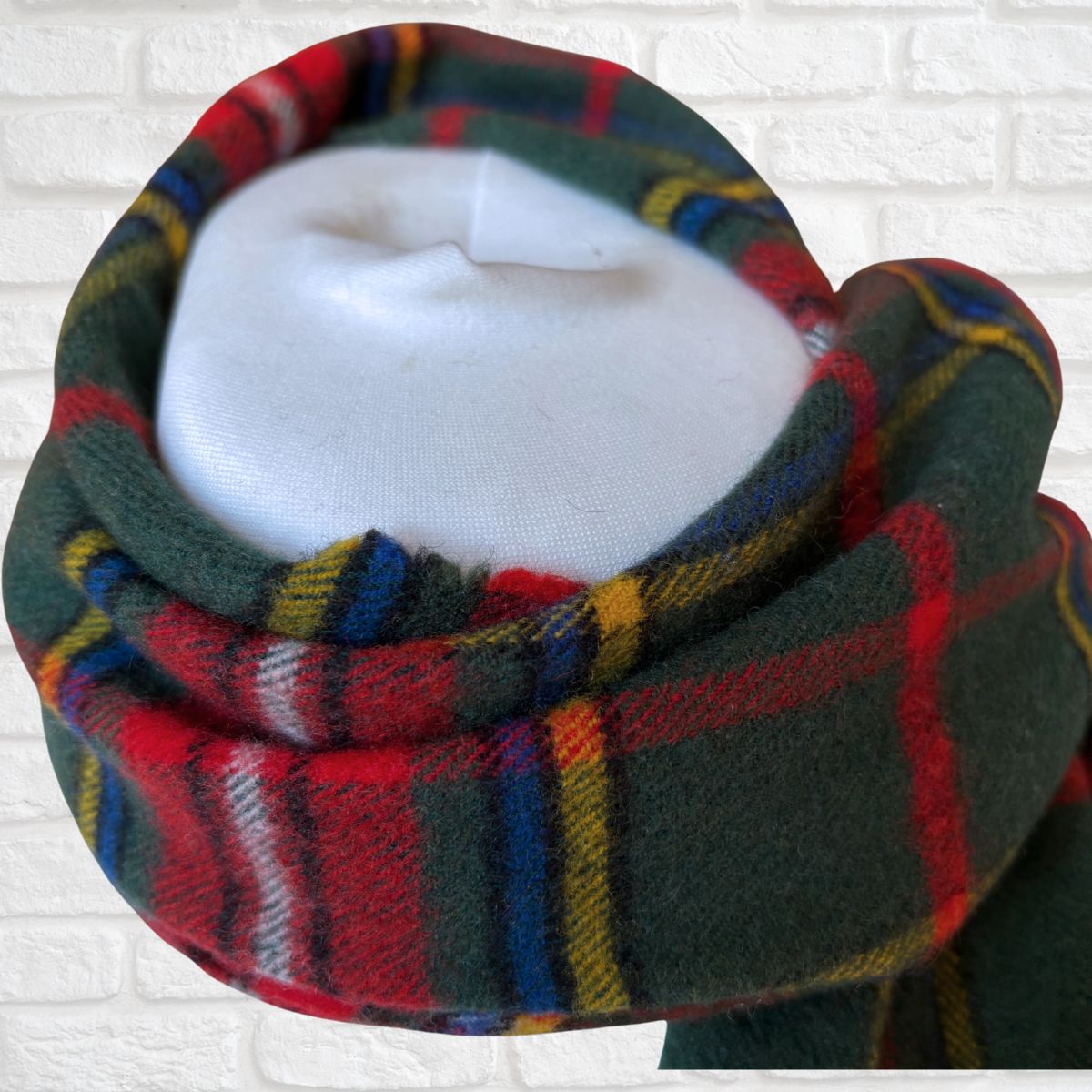 Plaid scarf on a mannequin head against a white brick wall background