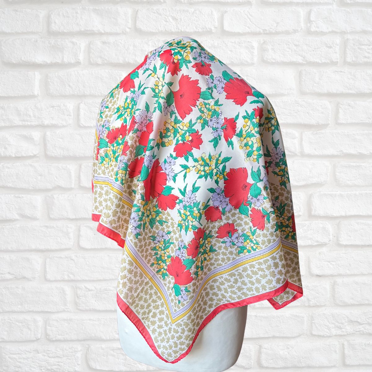Floral patterned scarf on a mannequin against a white brick wall background