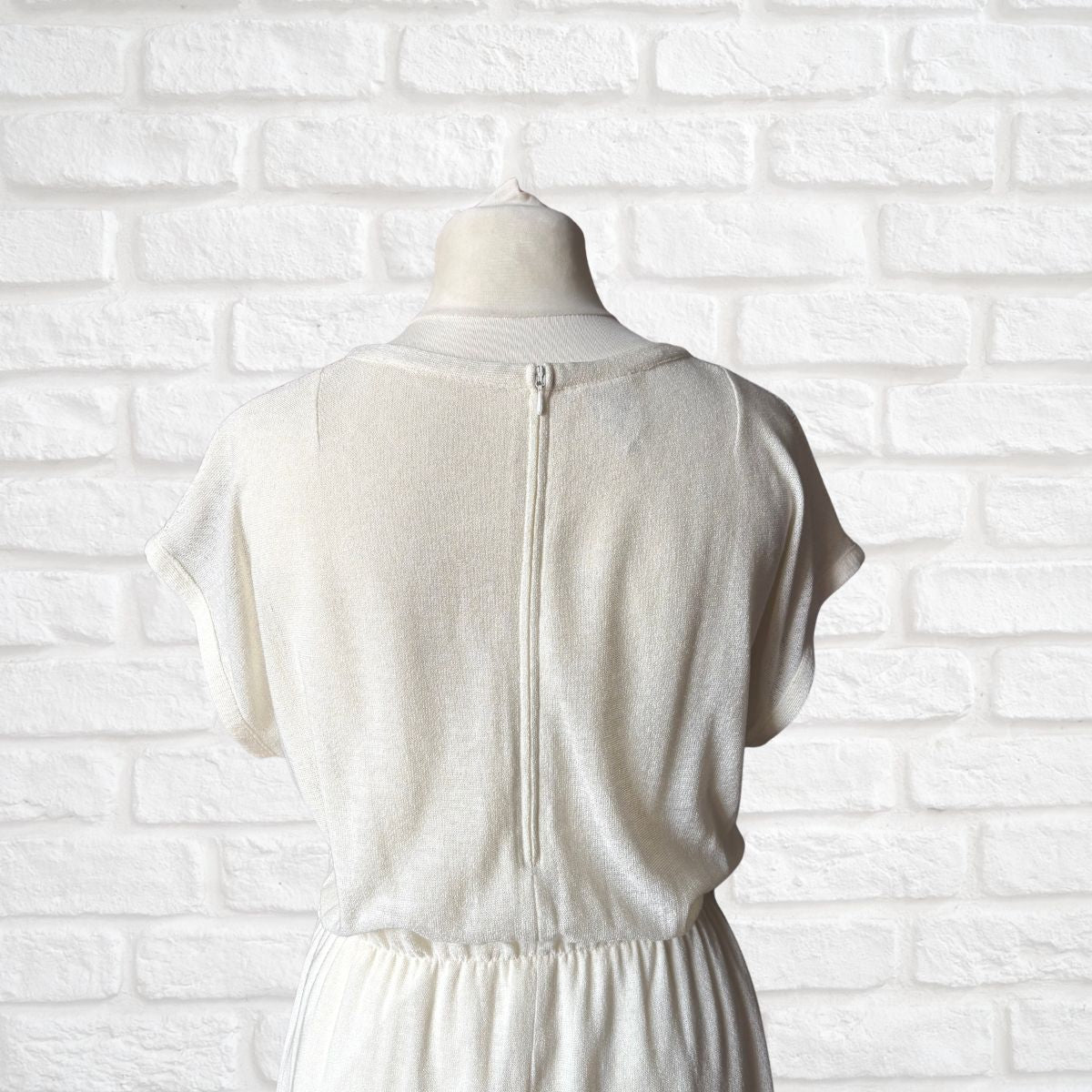 Off White dress on a mannequin against a white brick wall