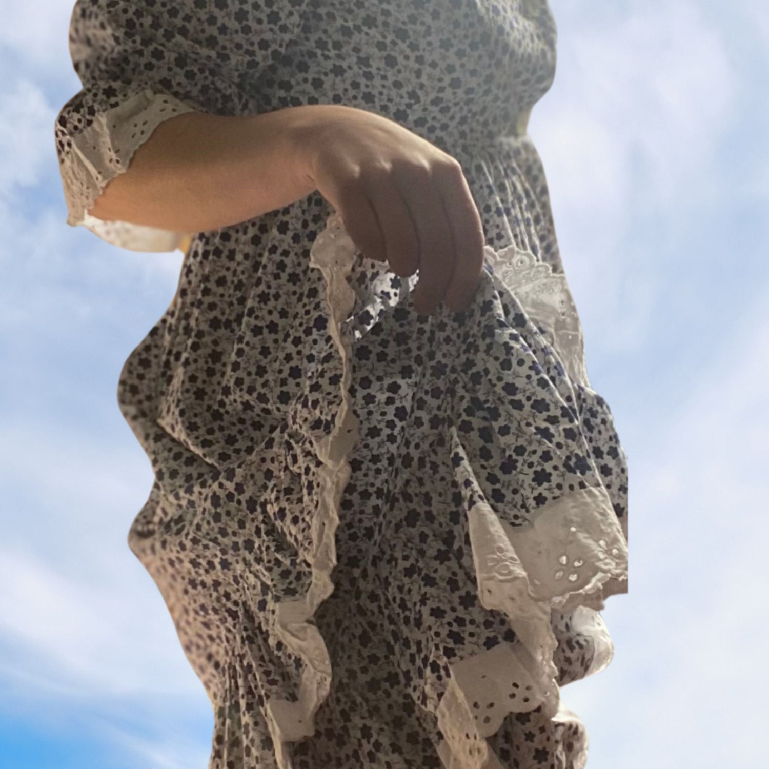 A person wearing a blue and white 70s maxi dress with white embroidery anglaise trim