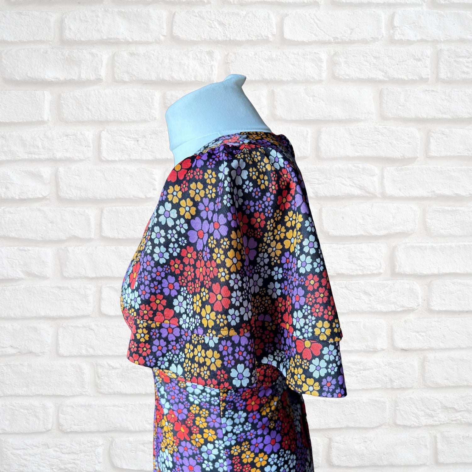 A two tiered angel sleeve printed with purple, red, white and yellow daisies on a black background. 70s mini dress