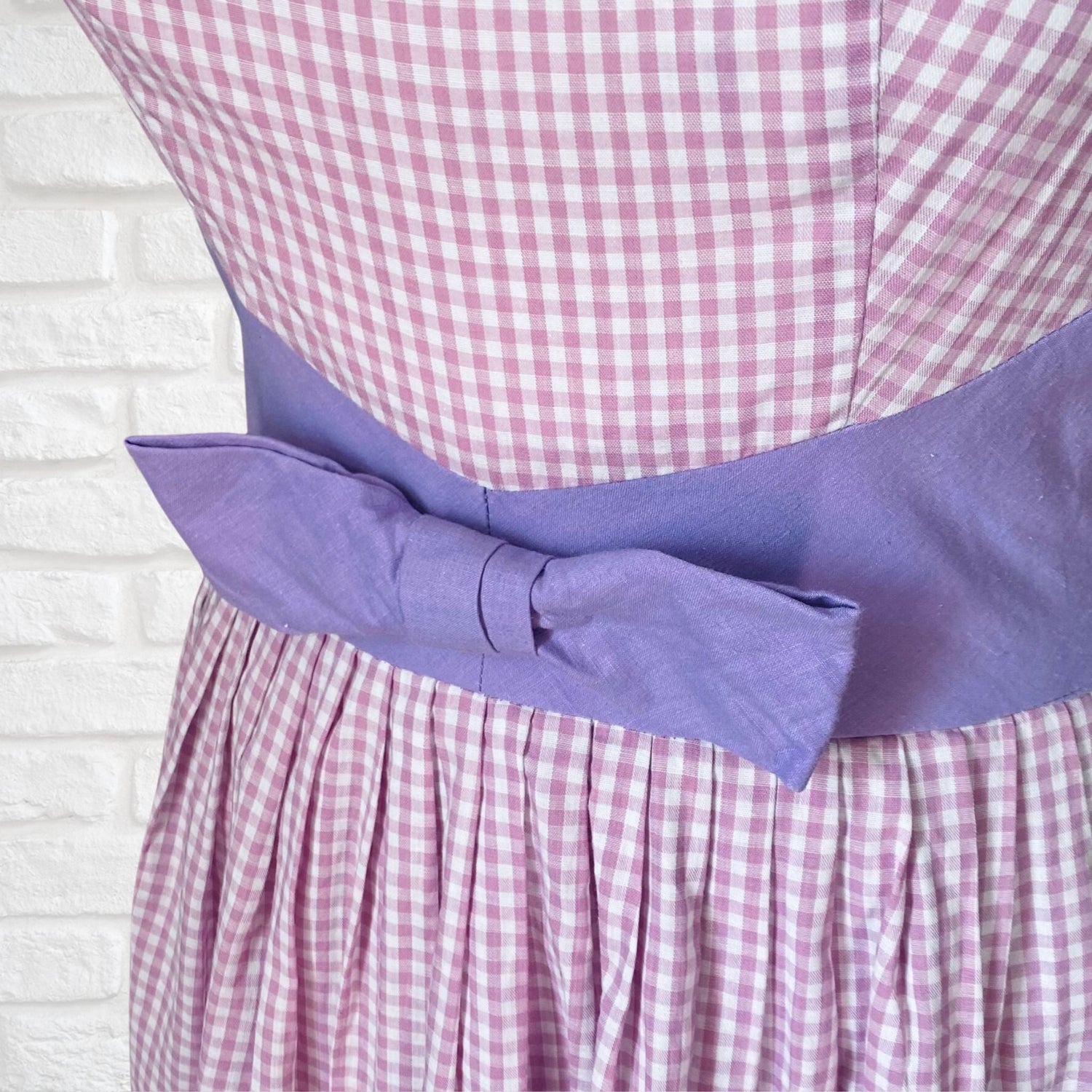 A lilac gingham 1950s cotton dress with a mauve bow at the waist