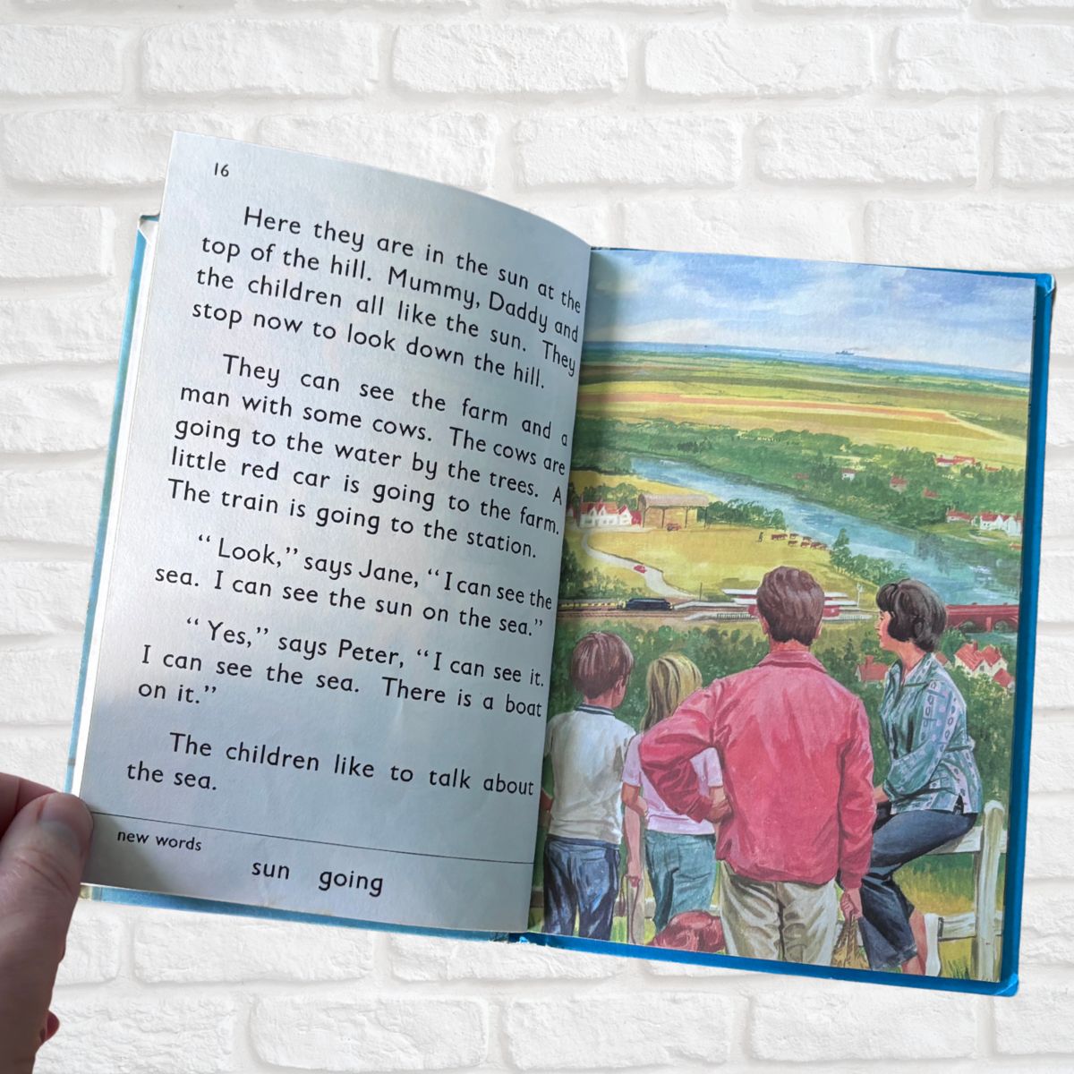 Open book with a colorful illustration of a family on a hilltop and text.