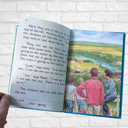 Open book with a colorful illustration of a family on a hilltop and text.