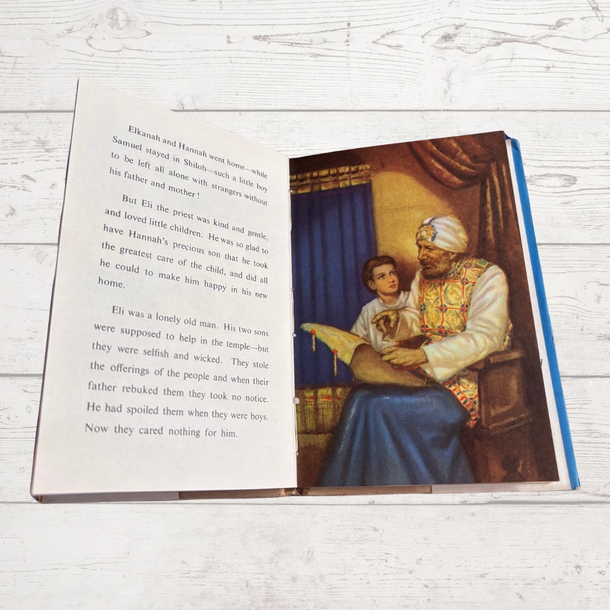 Open book with a colorful illustration of an older man and a young boy on a wooden surface.