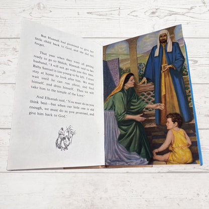 Open book with illustrated scene of a woman and child, and text on a white wooden surface.