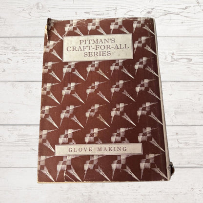 Book titled 'Pitman's Craft-for-All Series: Glove Making' with a patterned cover on a wooden surface