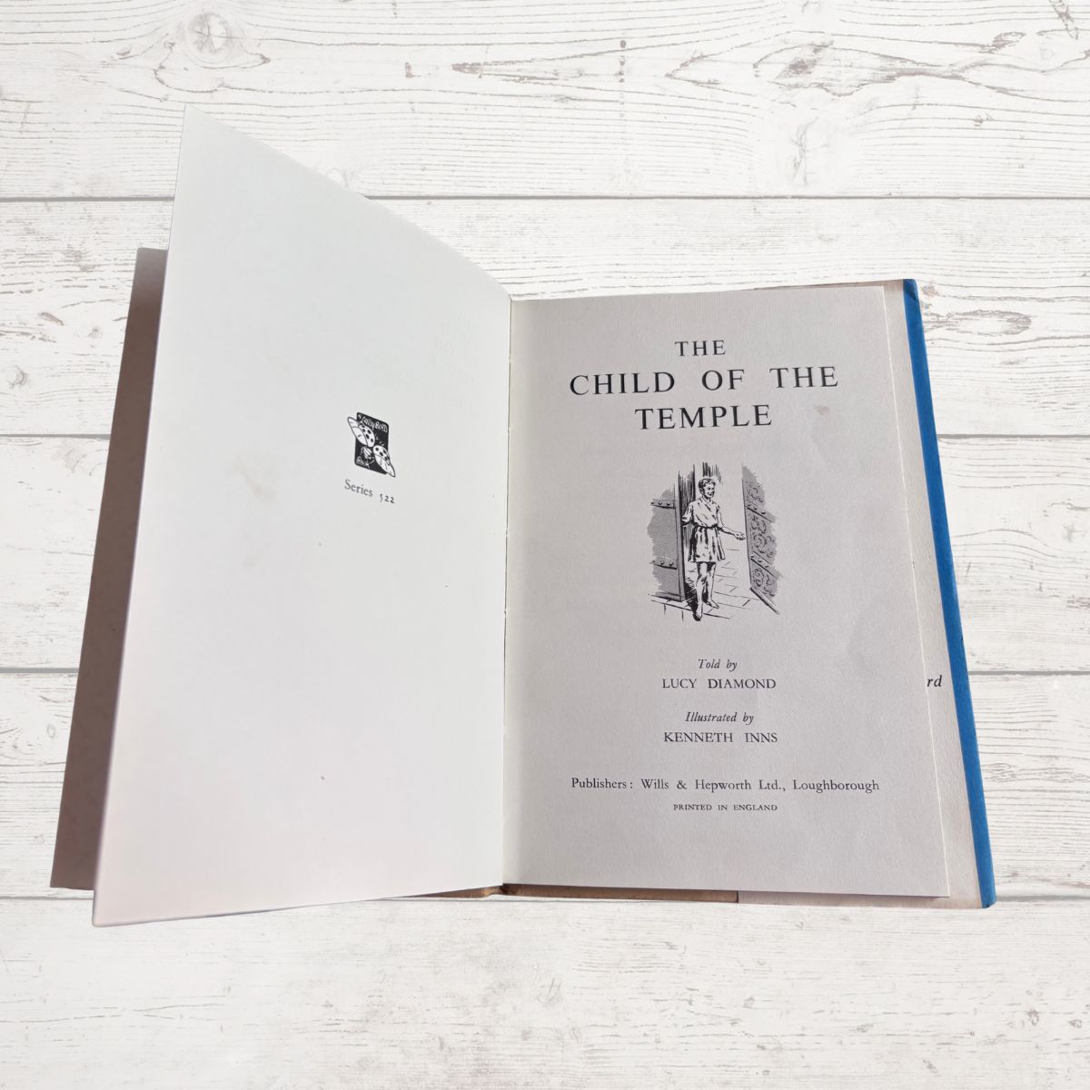 Open book titled 'The Child of the Temple' on a wooden surface
