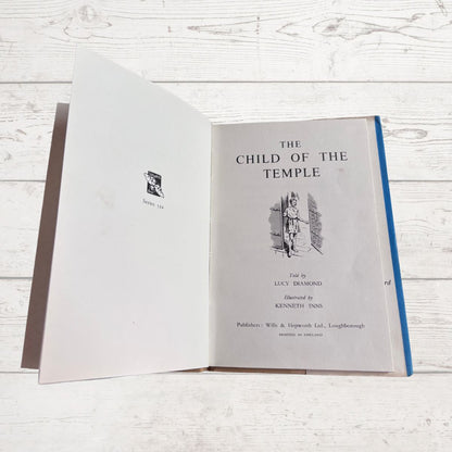 Open book titled 'The Child of the Temple' on a wooden surface