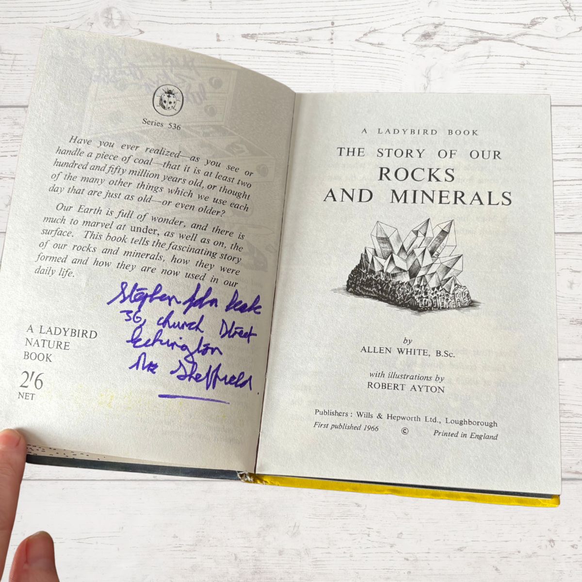 Open book titled 'The Story of Our Rocks and Minerals' with a signature on a white background