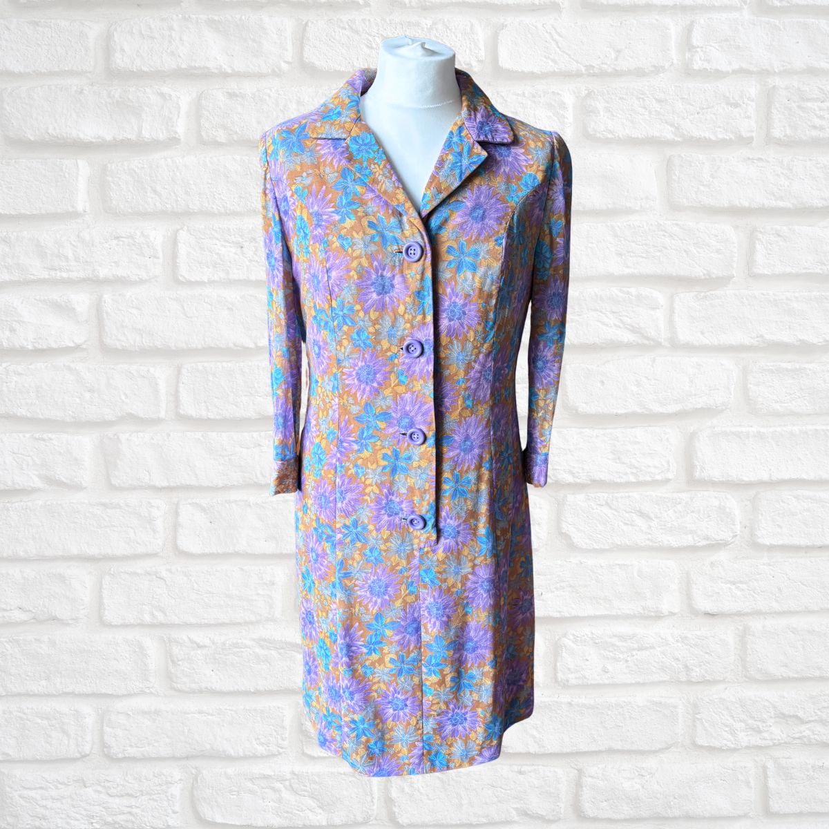 Floral patterned dress on a mannequin against a white brick wall background