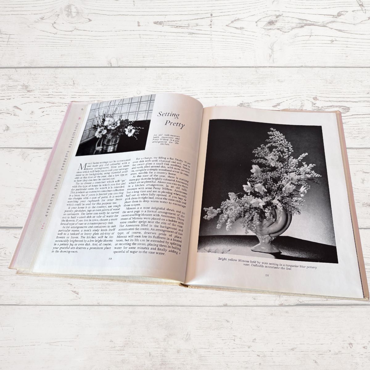 Open book on a wooden surface with black and white photos of floral arrangements.