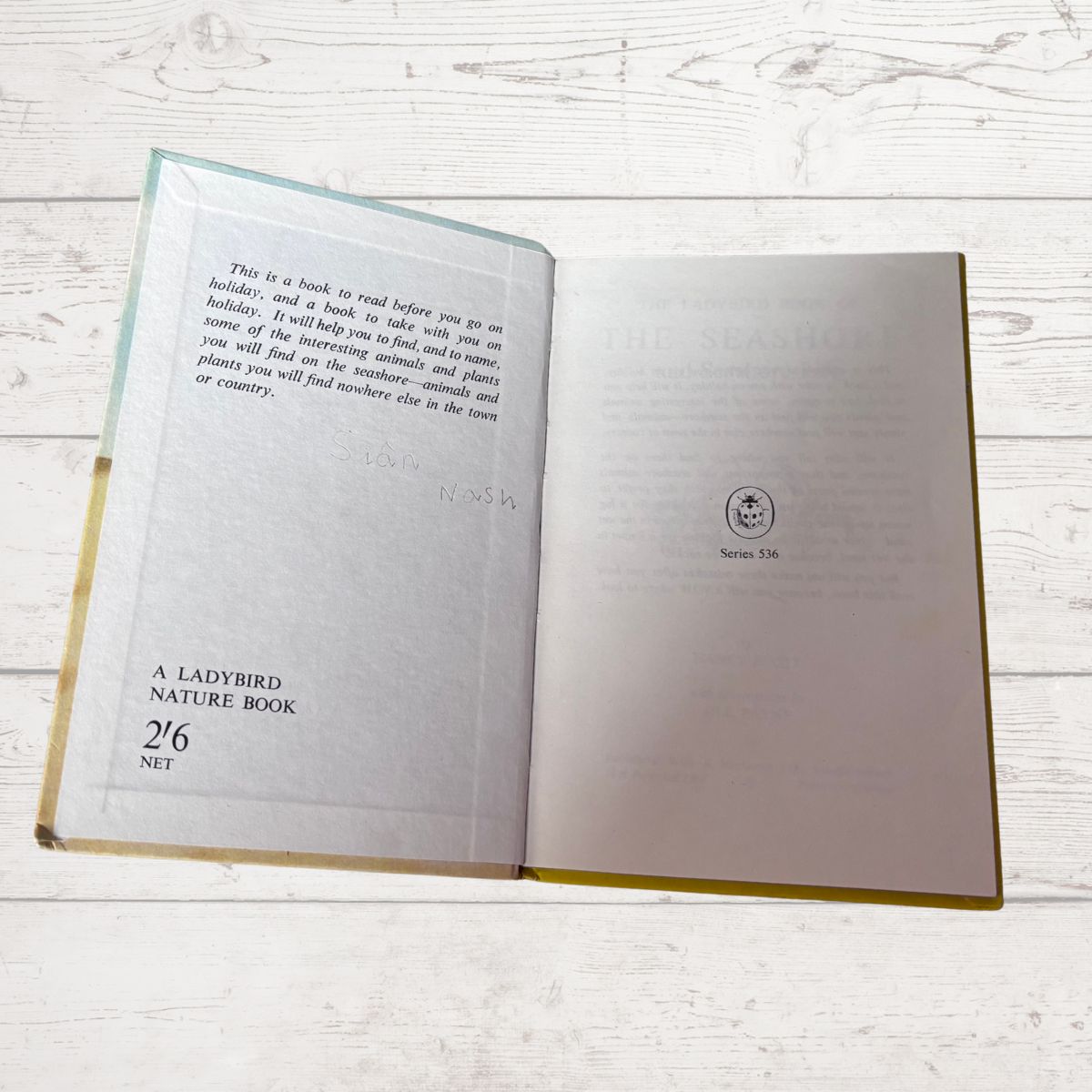 Open book with text and a Ladybird logo on a wooden surface