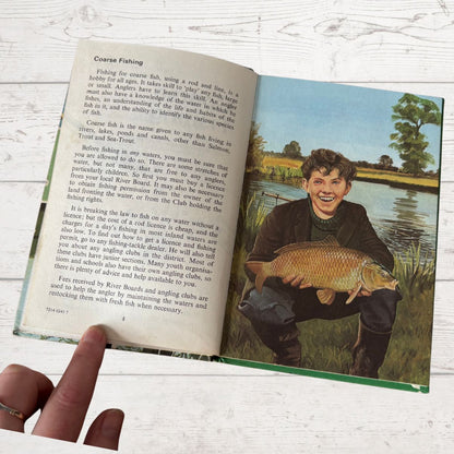 Open book with a colorful illustration of a boy holding a fish, on a wooden surface.
