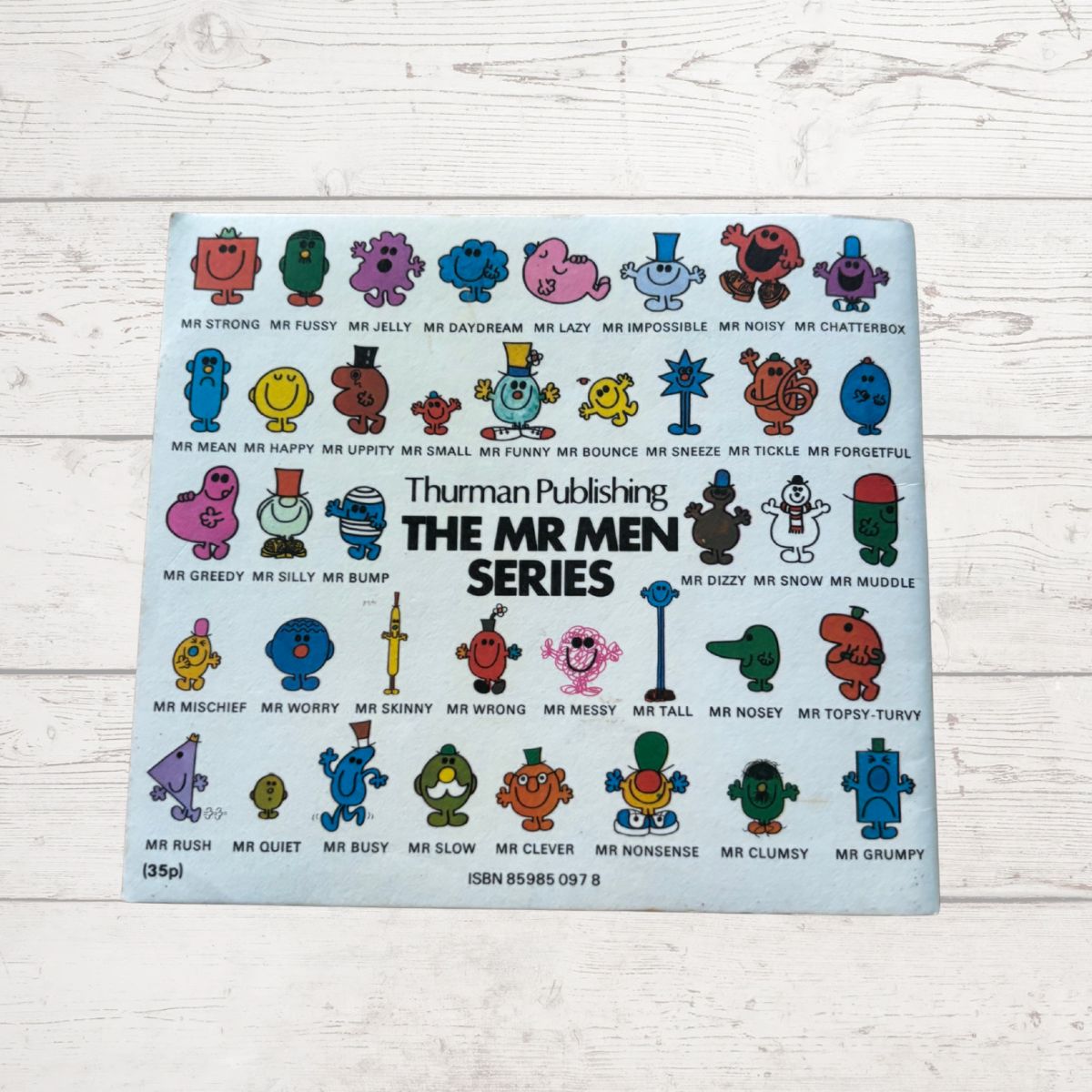 Placemat with colorful Mr Men illustrations on a light wooden surface