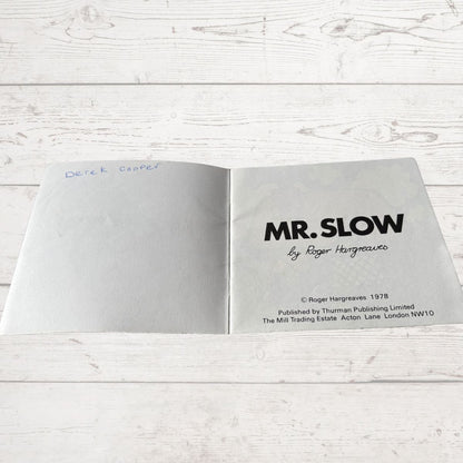 Open book with 'MR. SLOW' title on a wooden surface