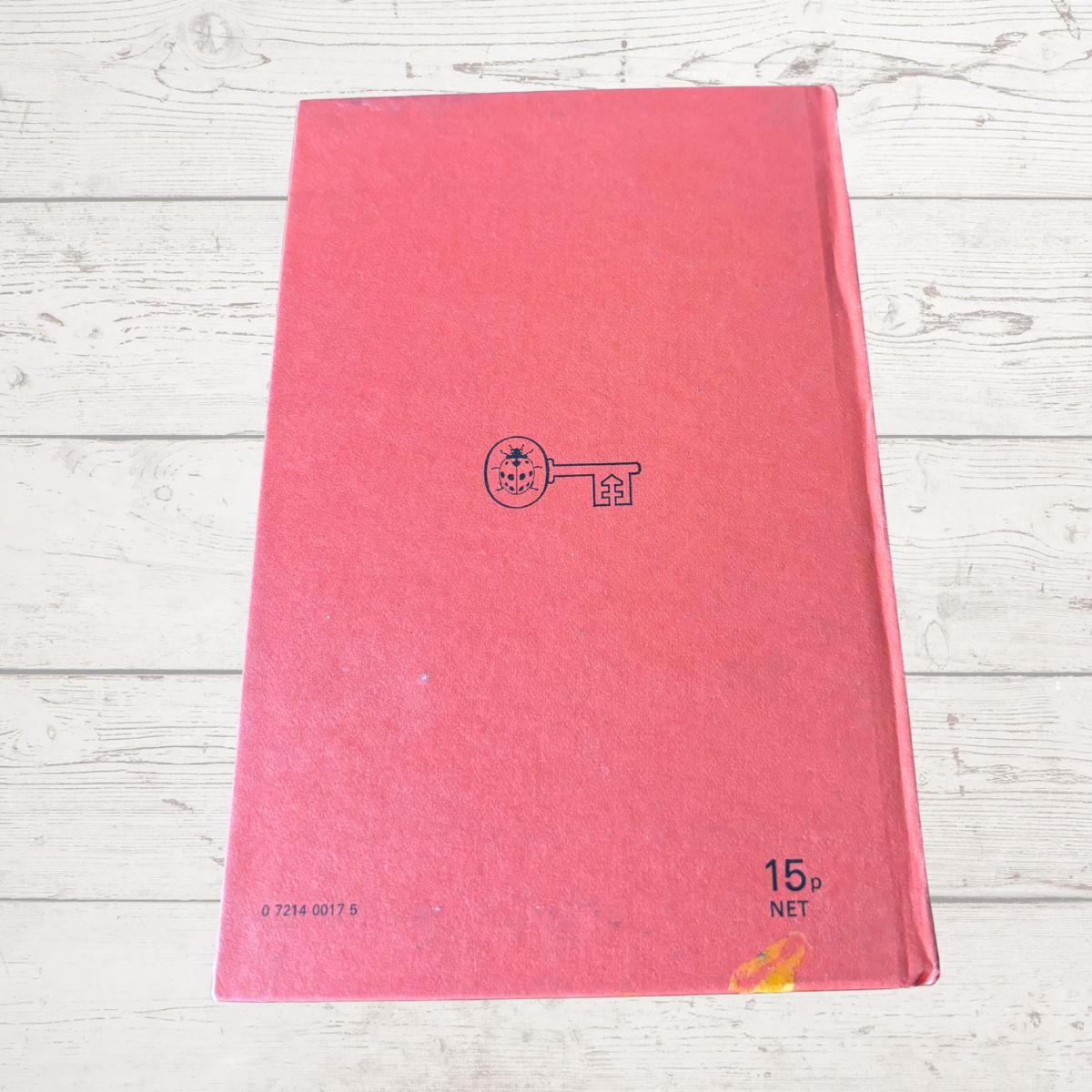 Red book with a logo on a light wooden surface