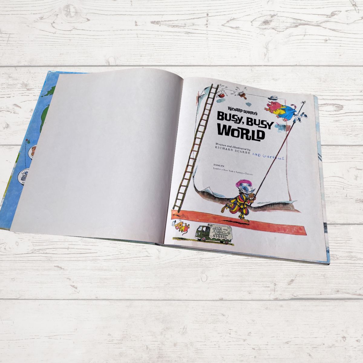 Open book titled 'Busy, Busy World' on a wooden surface
