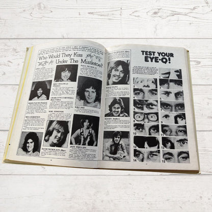 Open book with black and white photos and text on a light wooden surface