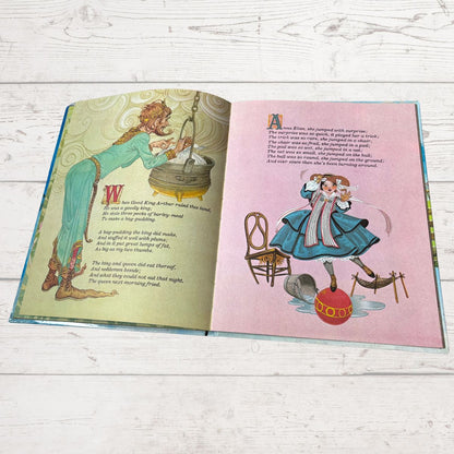 An open children's picture book spread on a whitewashed wood surface, showing illustrated pages with text and colorful drawings.