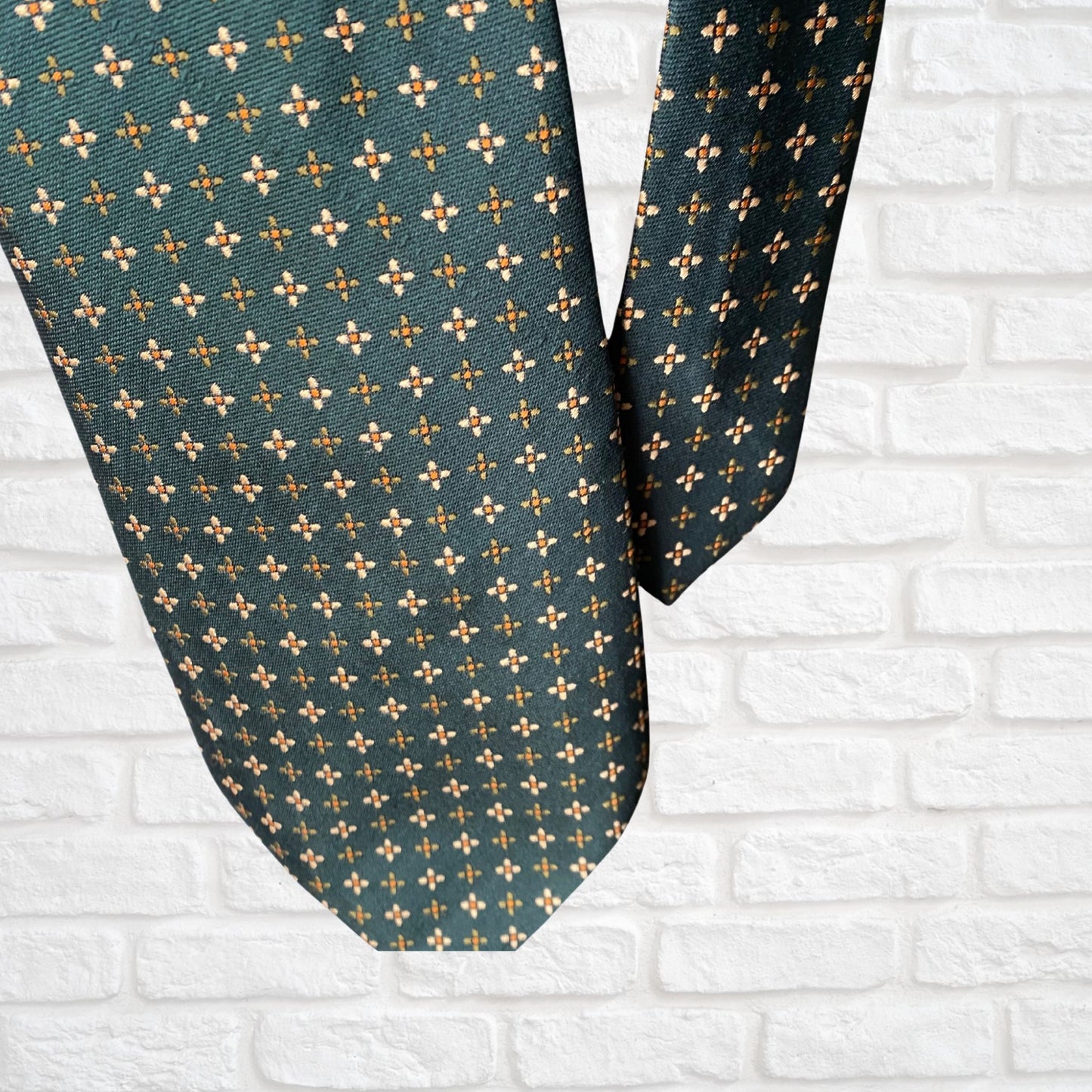 Close up of a green, orange and white geometric floral  print vintage 70s tie